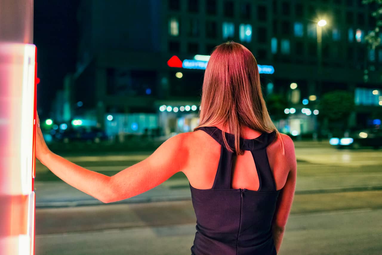A young woman standing on the street at night