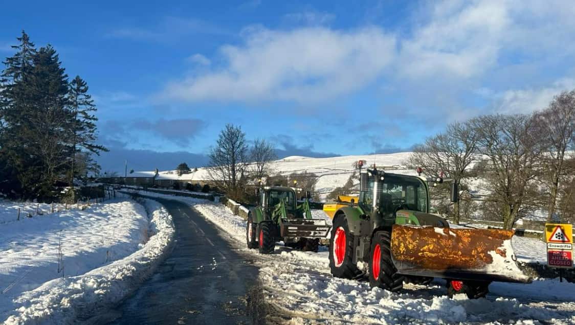 Two ploughs beside a road in heavy snow.