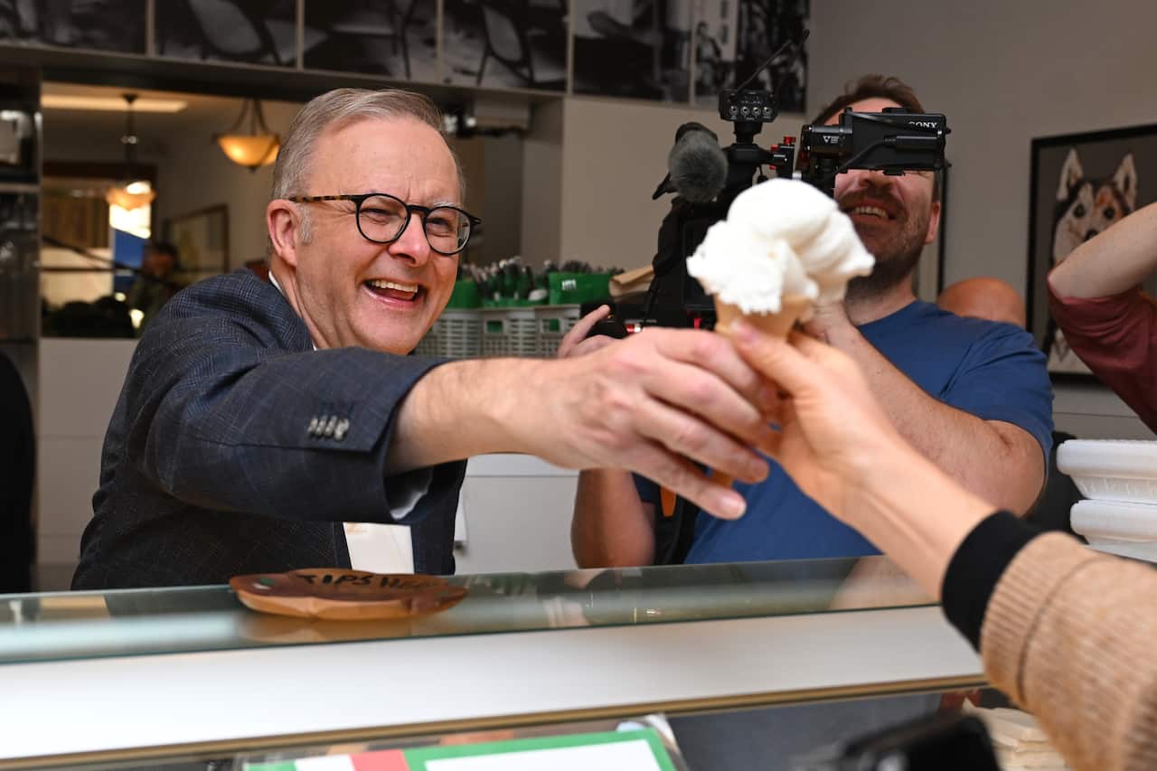 A man hands out an ice cream cone over a counter.