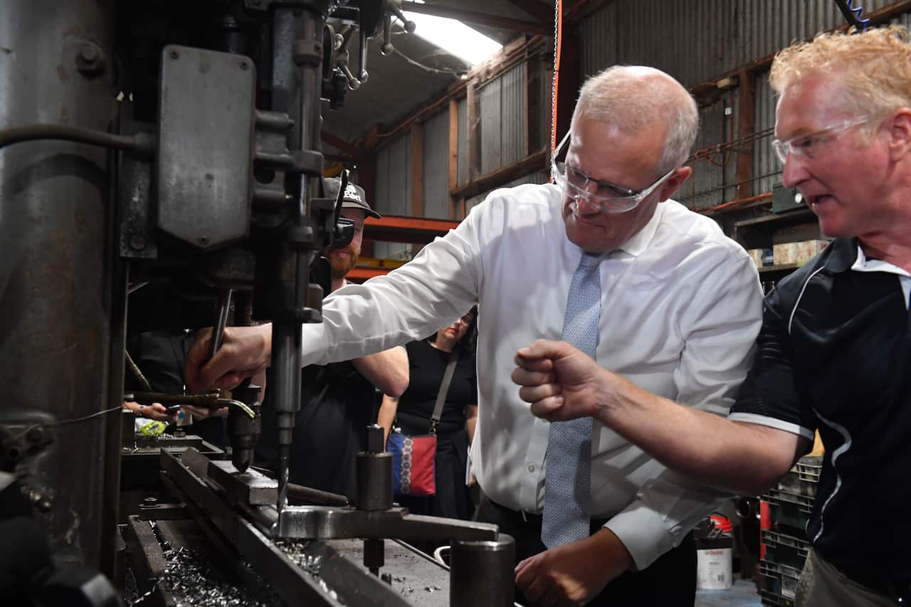 Prime Minister Scott Morrison is shown some machinery in a Sydney factory by a worker.