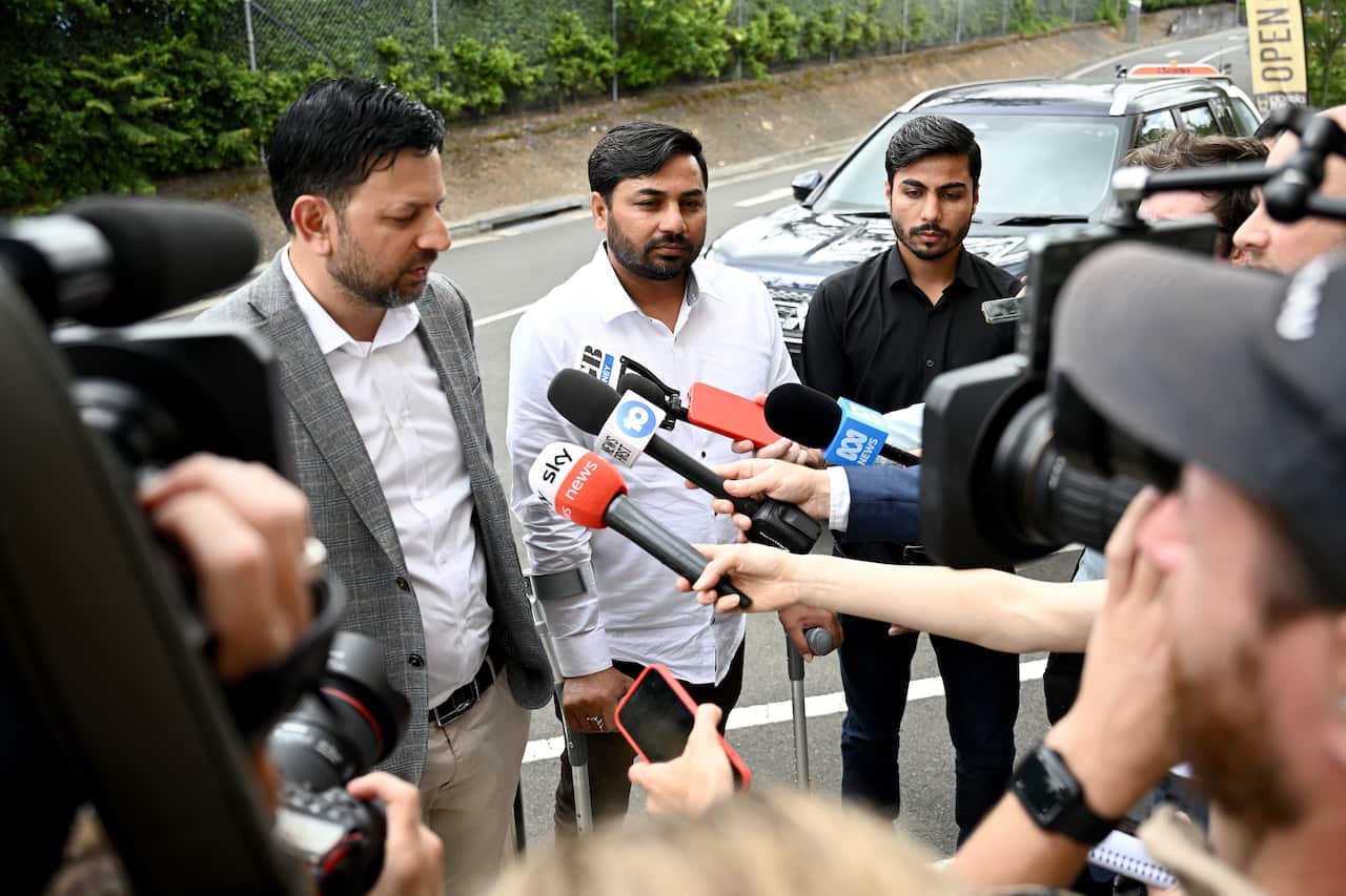 Three men being interviewed by journalists