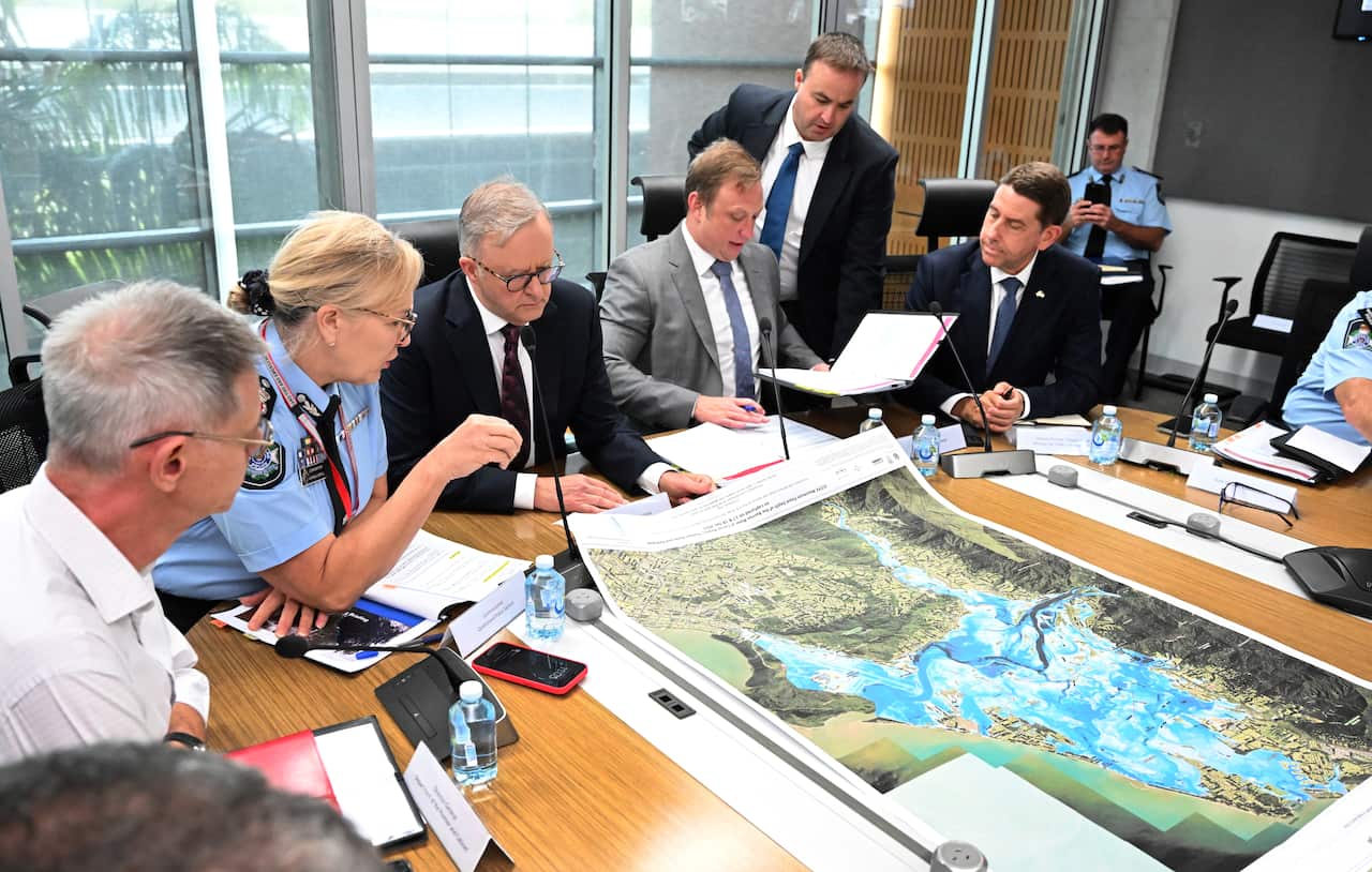 8 people sitting around a table looking at a map