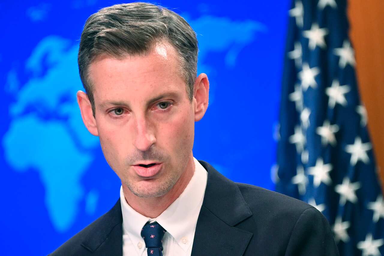 A man wearing a suit and tie speaking.