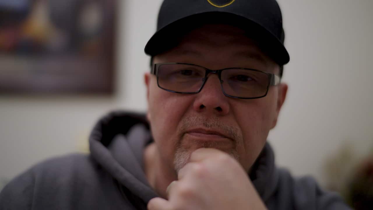 A close-up of a man wearing glasses and a cap