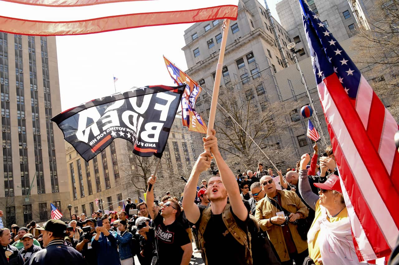 Demonstrators wave flags during a pro-Trump and anti-Trump rally while awaiting former president Trump's arraignment at New York County Criminal Court in New York City.