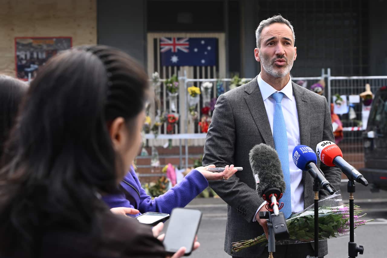 A man wearing a suit and tie speaking to reporters.
