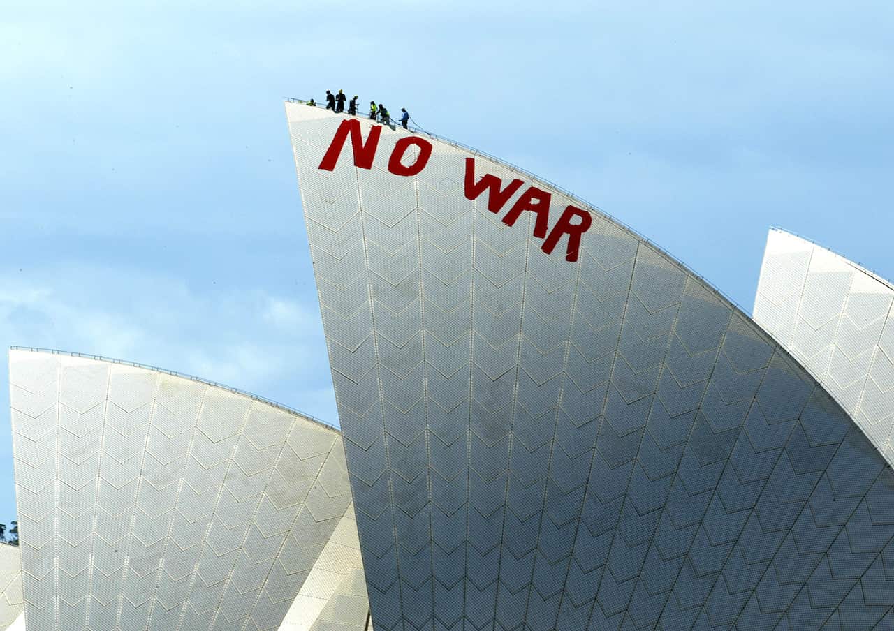 Red writing saying No War painted high on a sail of the Sydney Opera House.