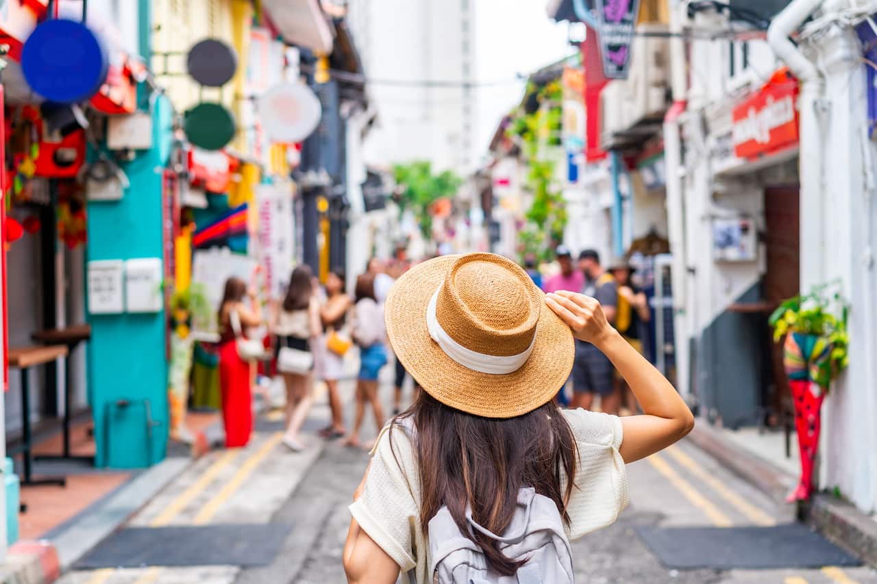 A woman walks through a colourful street.