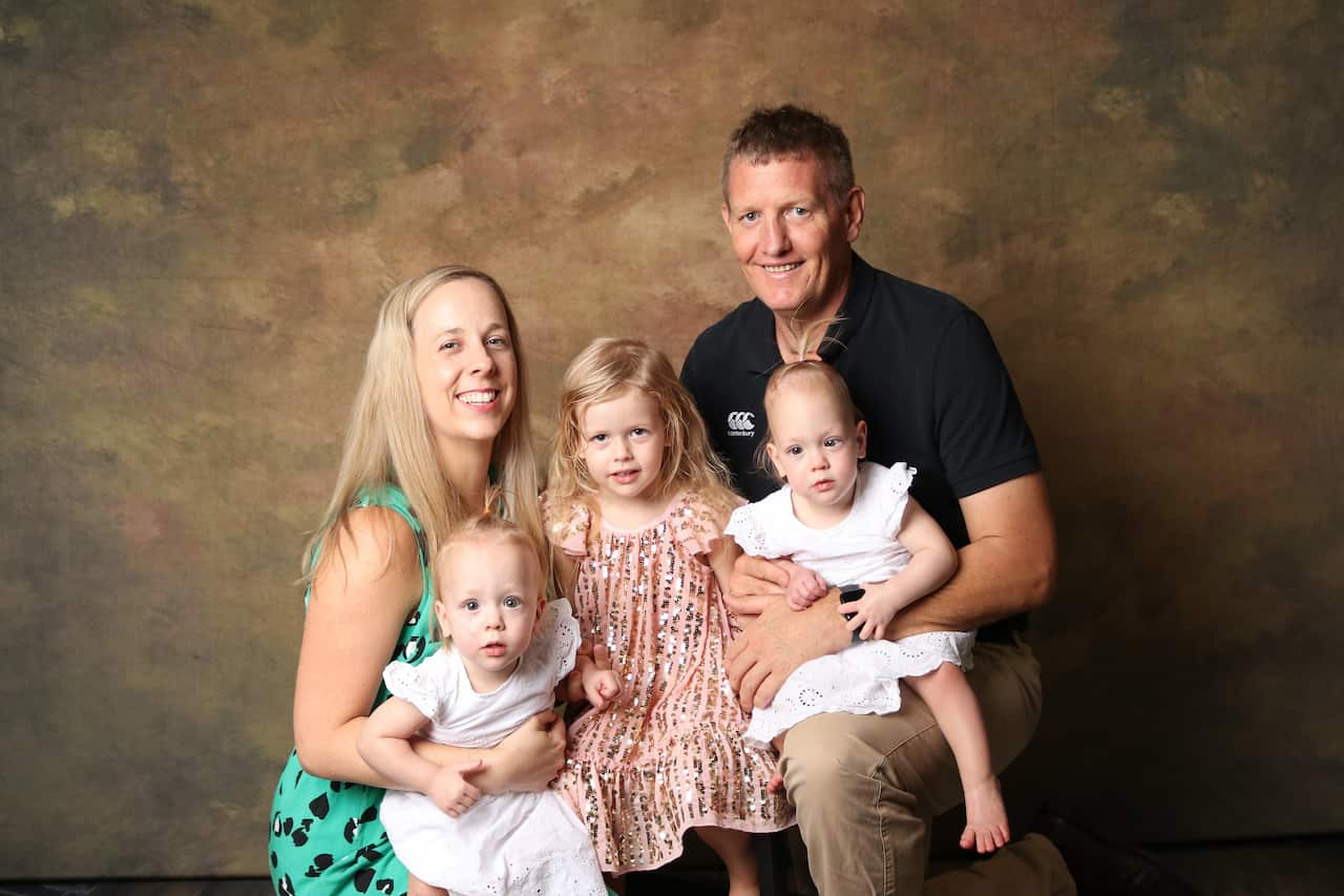 A photo of a family with a husband and wife and three young daughters