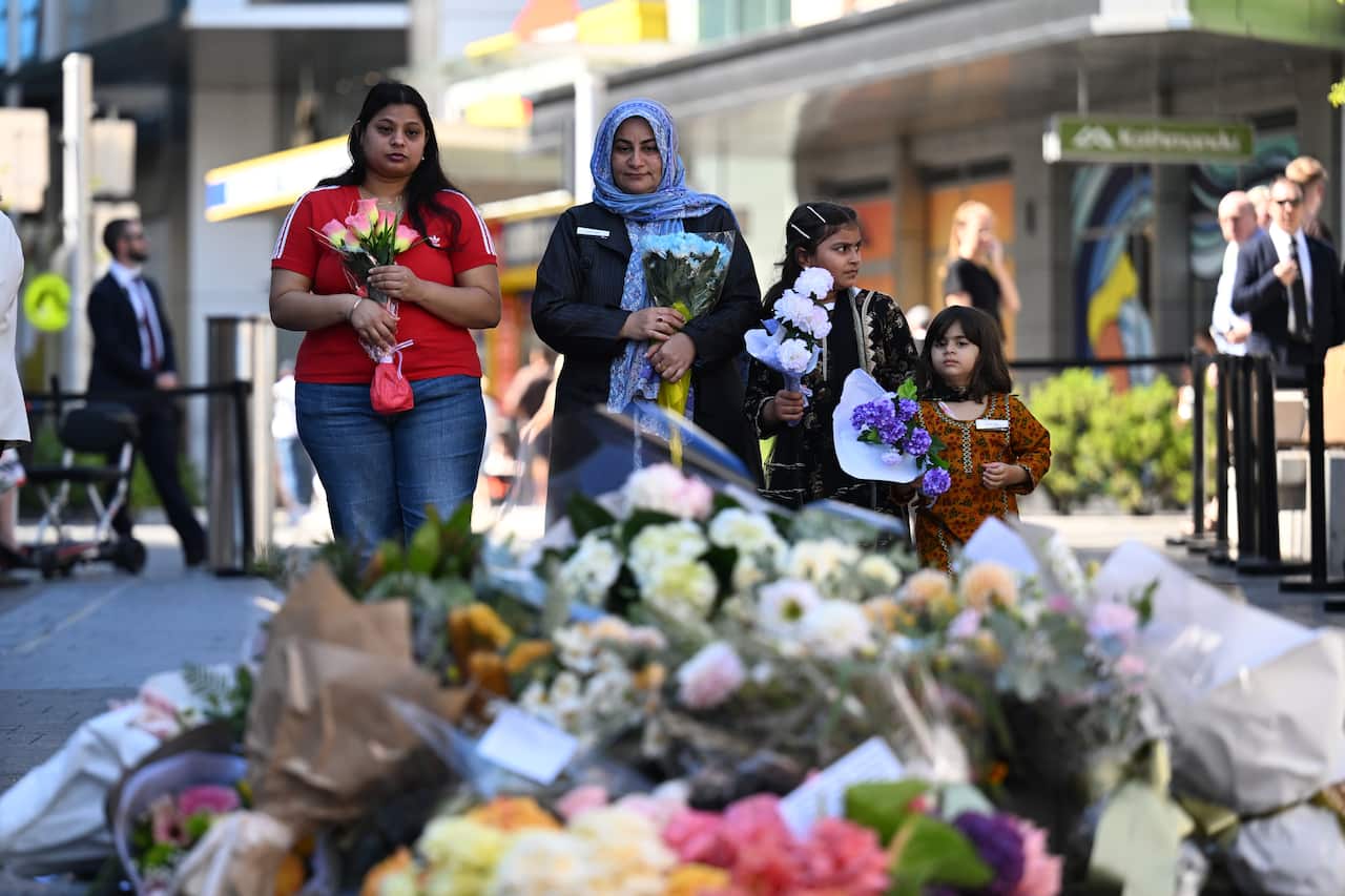 Two women and two children who are about to lay flowers at a memorial.