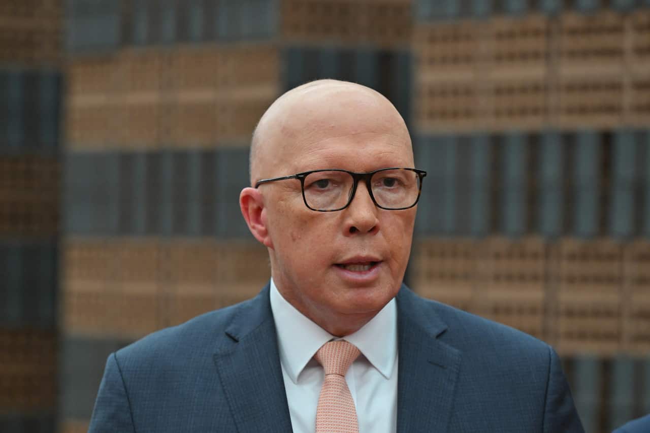 Peter Dutton standing in front of piles of bricks.