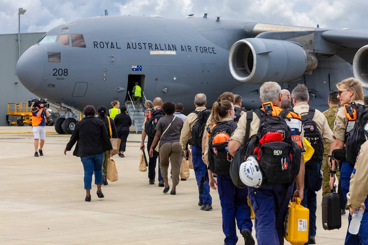 People waiting on a tarmac to board an evacuation flight