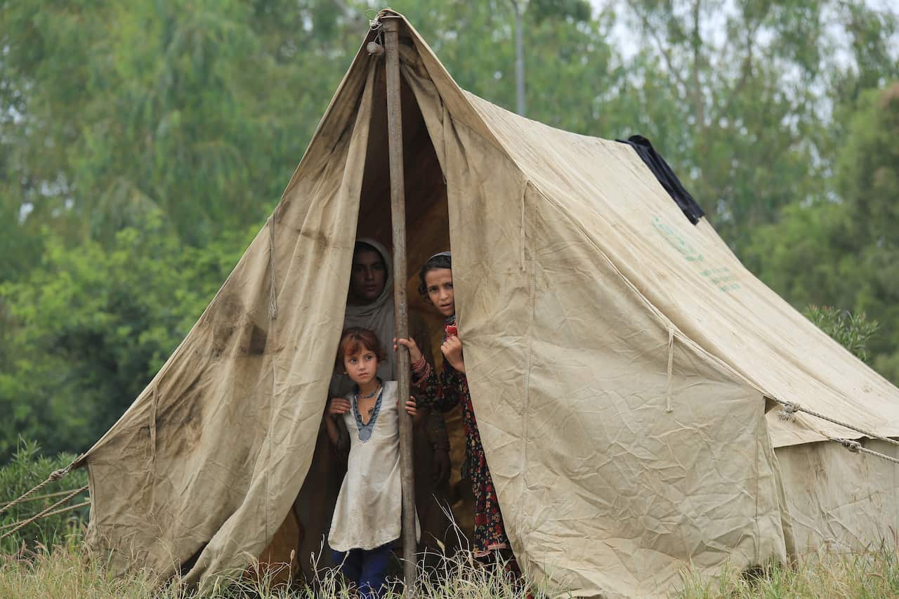 Young people peek through the openings of a tent. 