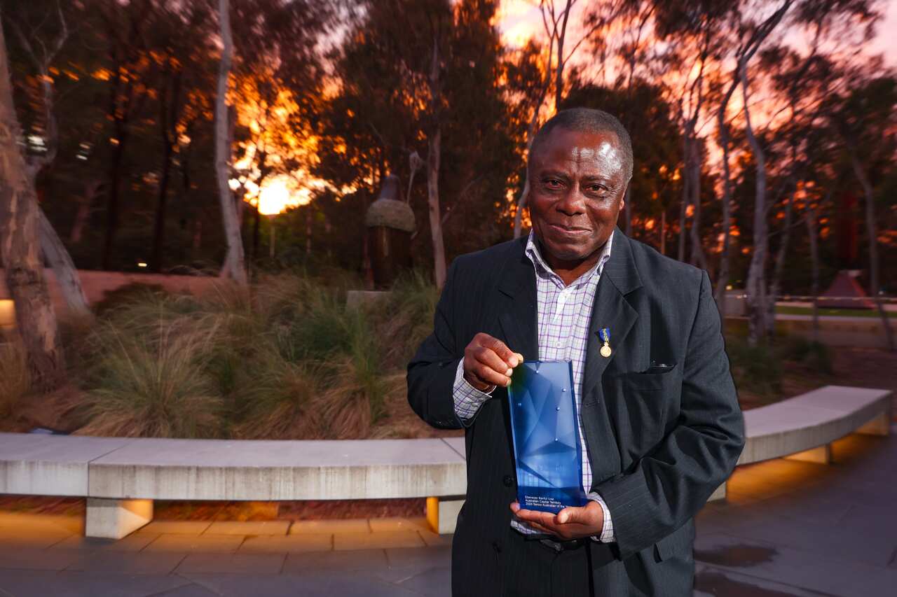 A man in a suit holding a trophy