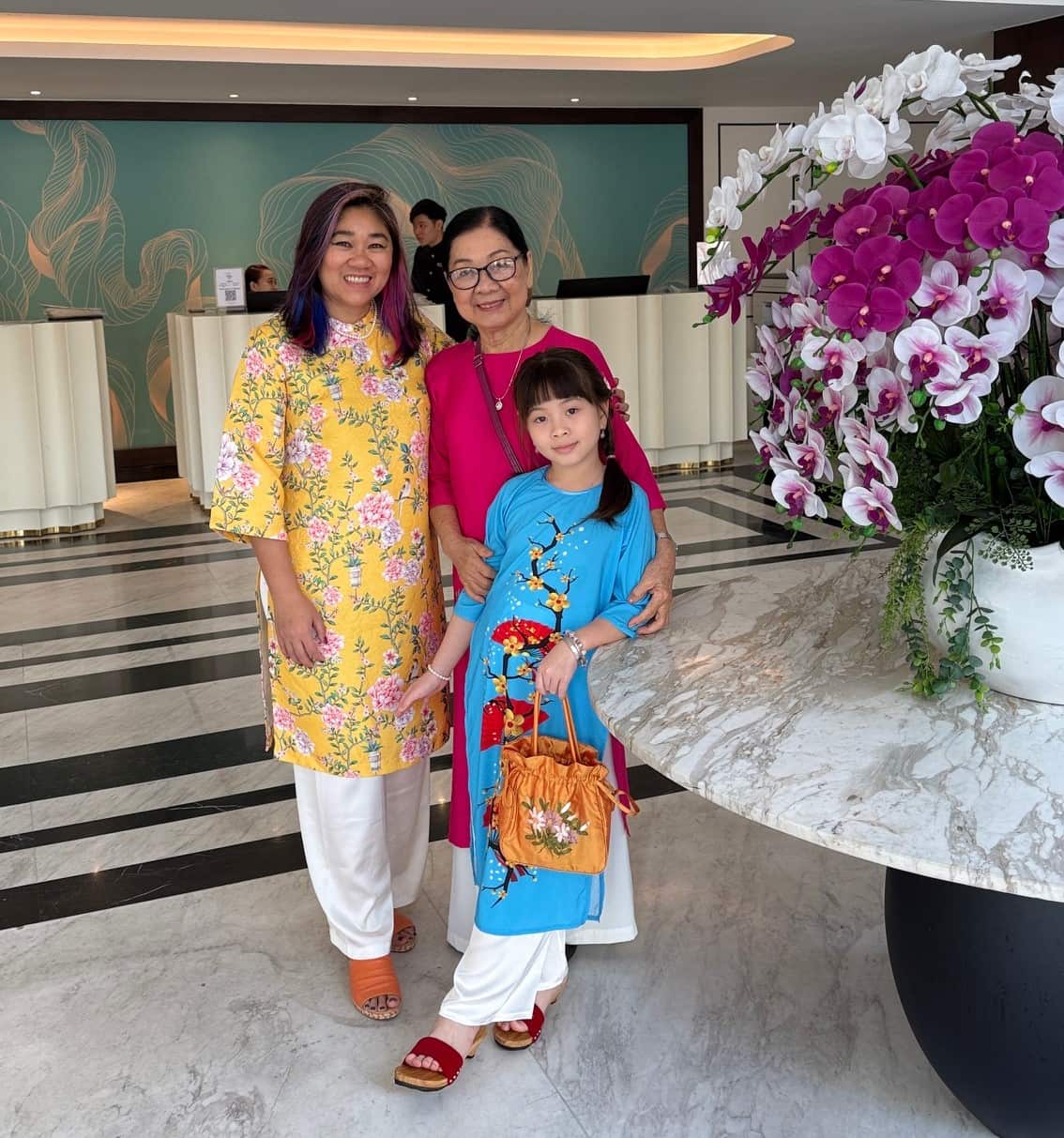 Two women and one girl pose in a lobby in traditional Vietnamese garb.