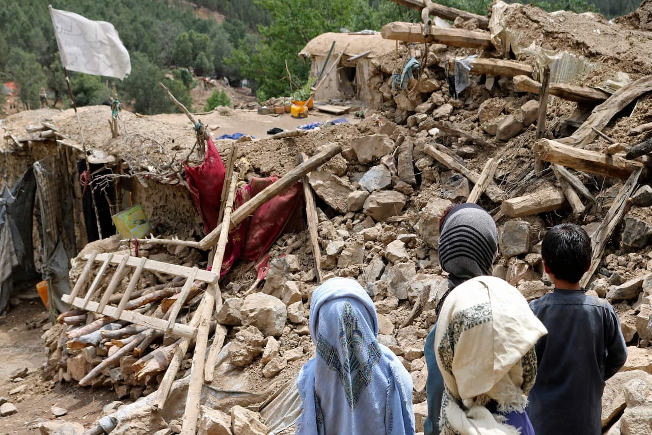 Afghan children stand near a house that was destroyed in an earthquake in the Spera District of the southwestern part of Khost Province, Afghanistan.