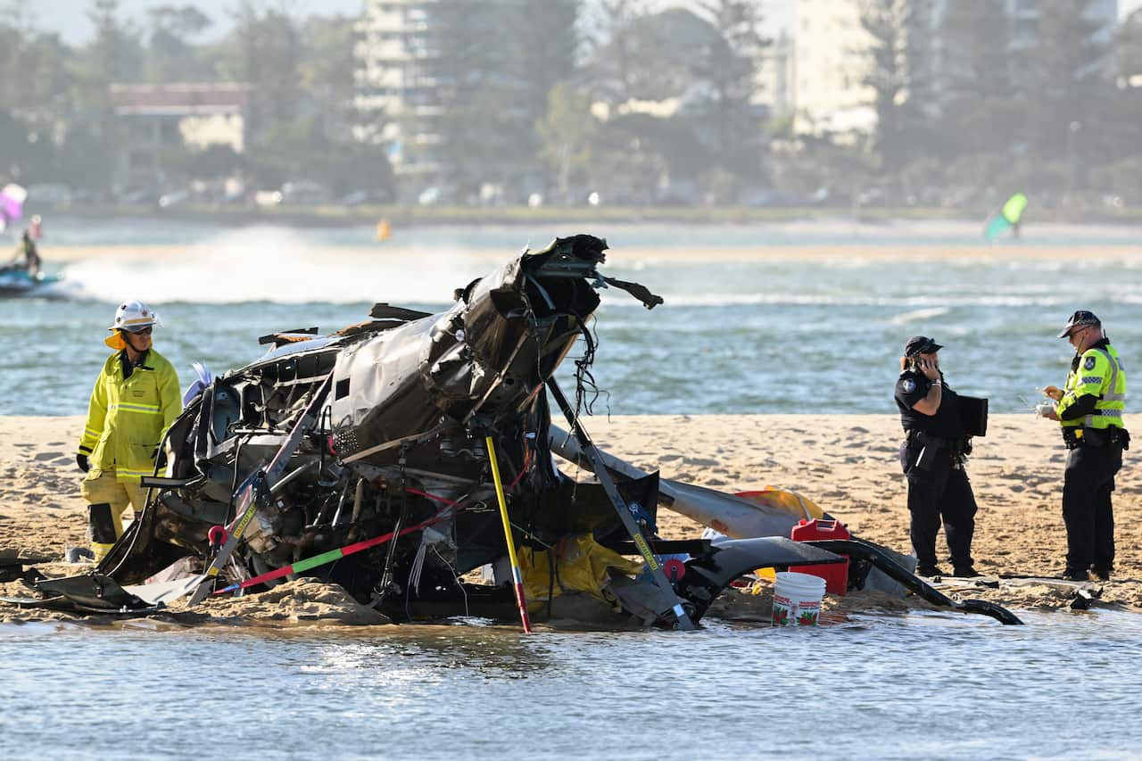 First responders stand next to the wreckage of the helicopter.