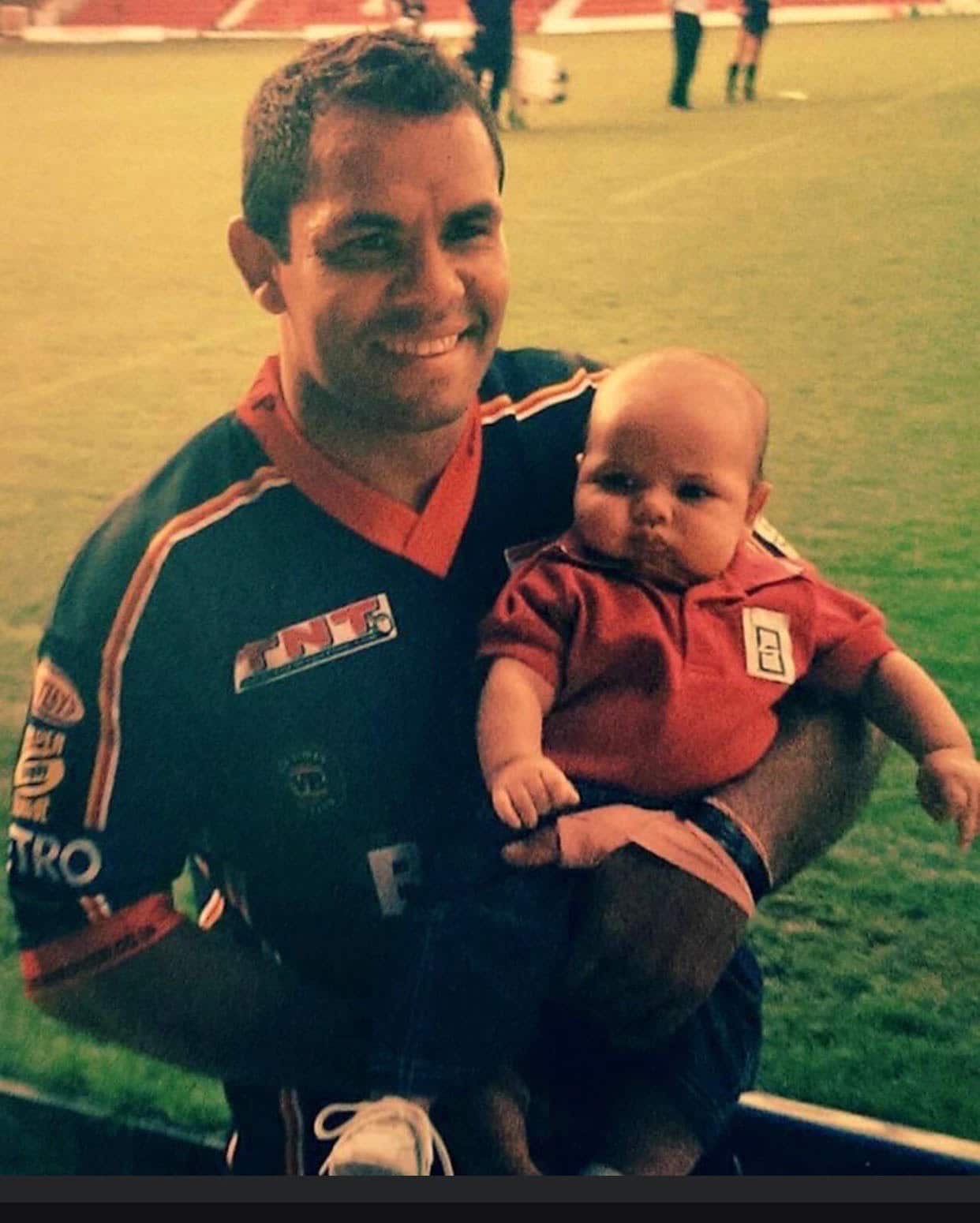 Father on the sideline after a game holding baby son