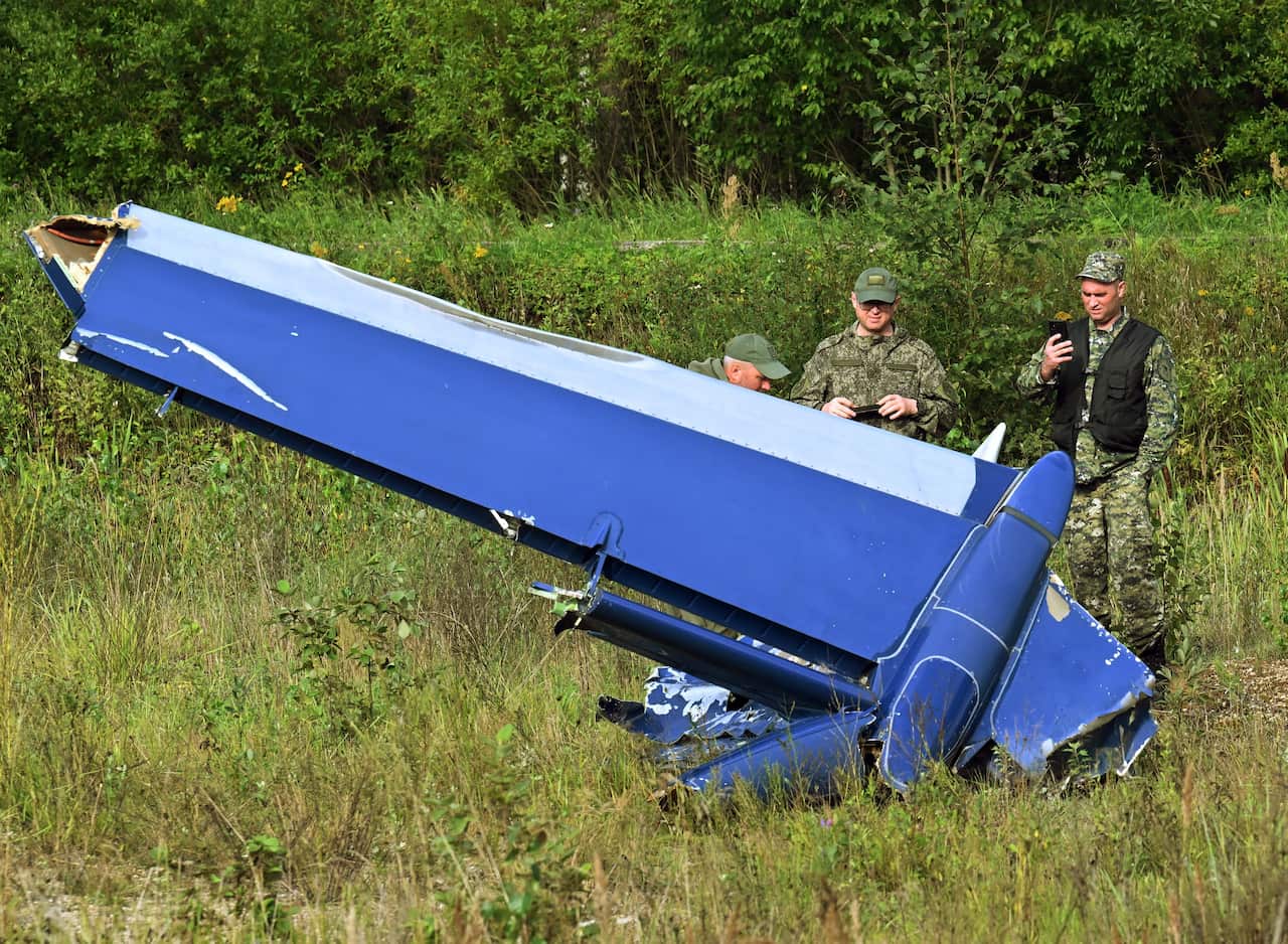 Security forces inspecting a piece of debris at the site of a plane crash.