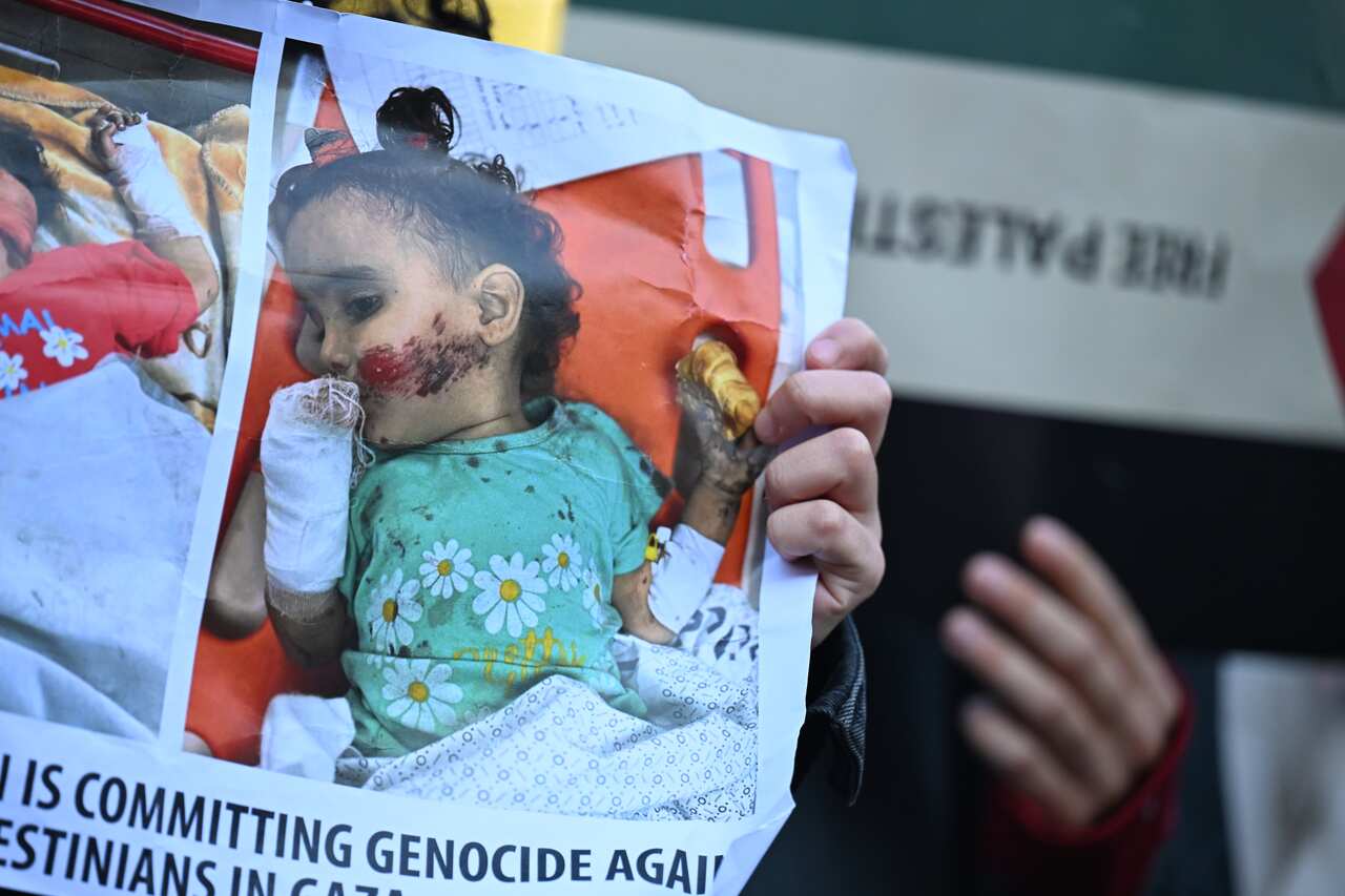 A protester holds up an poster with the image of a severely injured young girl.