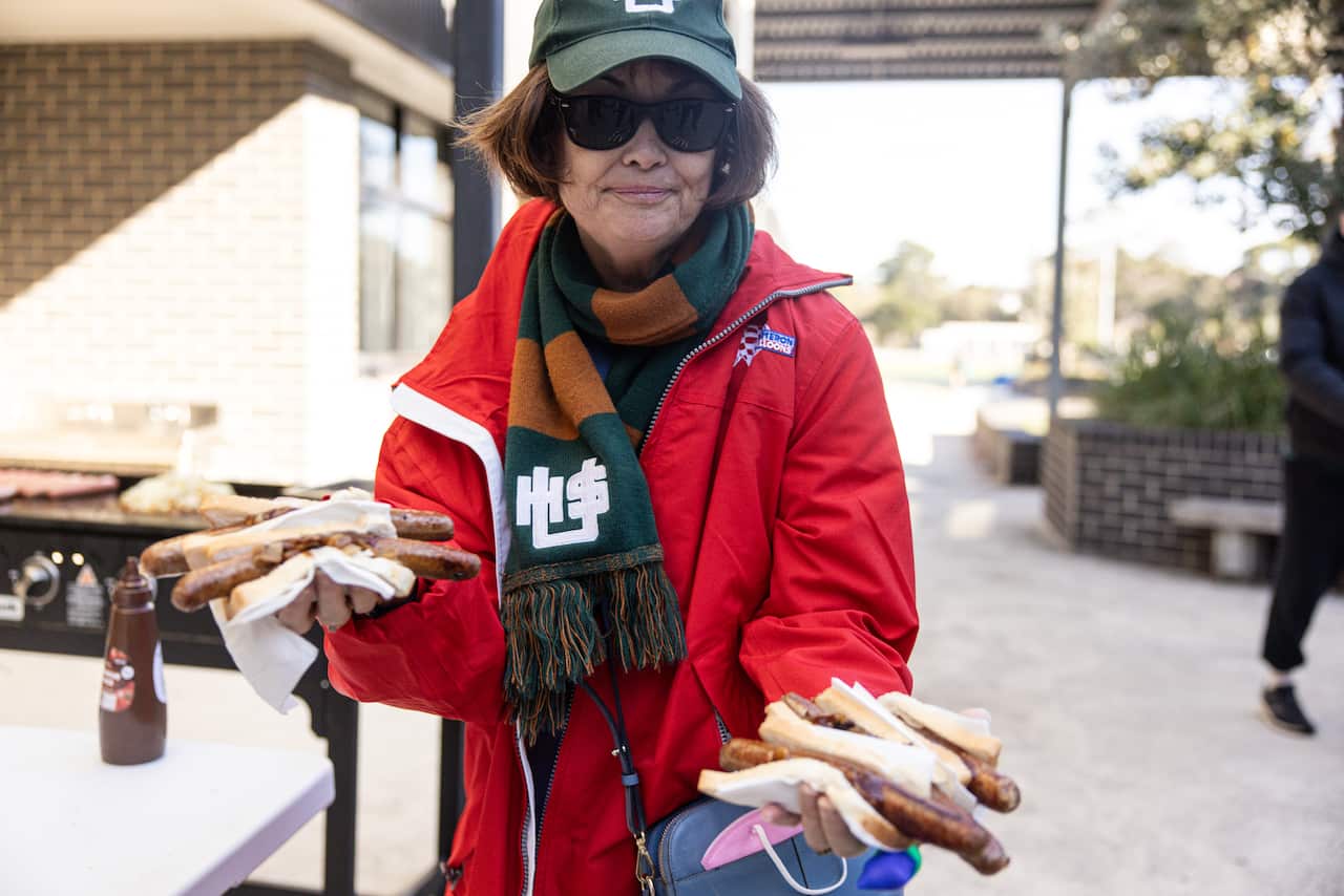 A woman holding a number of hot dogs outside a polling place