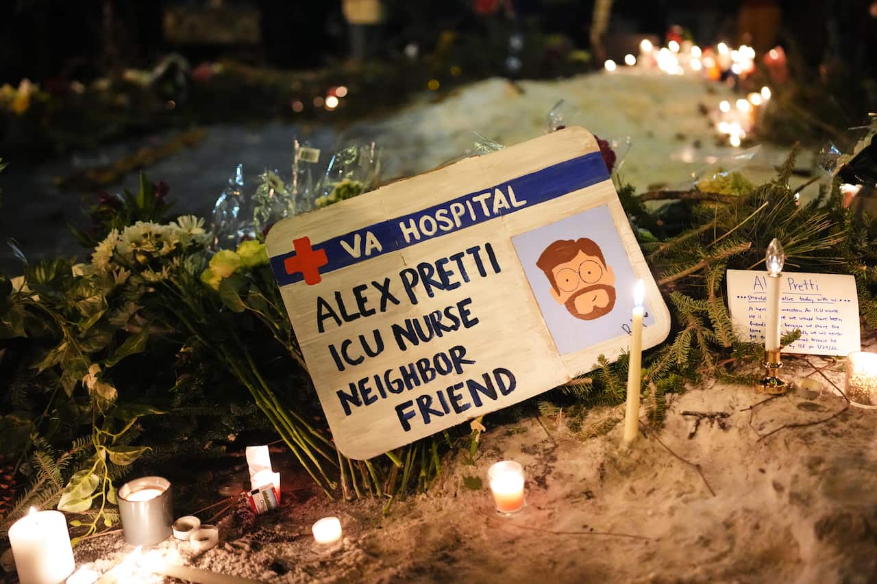 A small memorial to a man called Alex Pretti, surrounded by candles on the ground.
