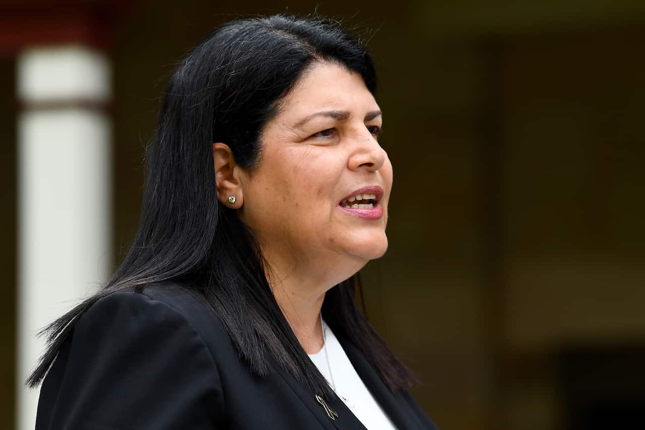 A woman with black hair in a black blazer speaking