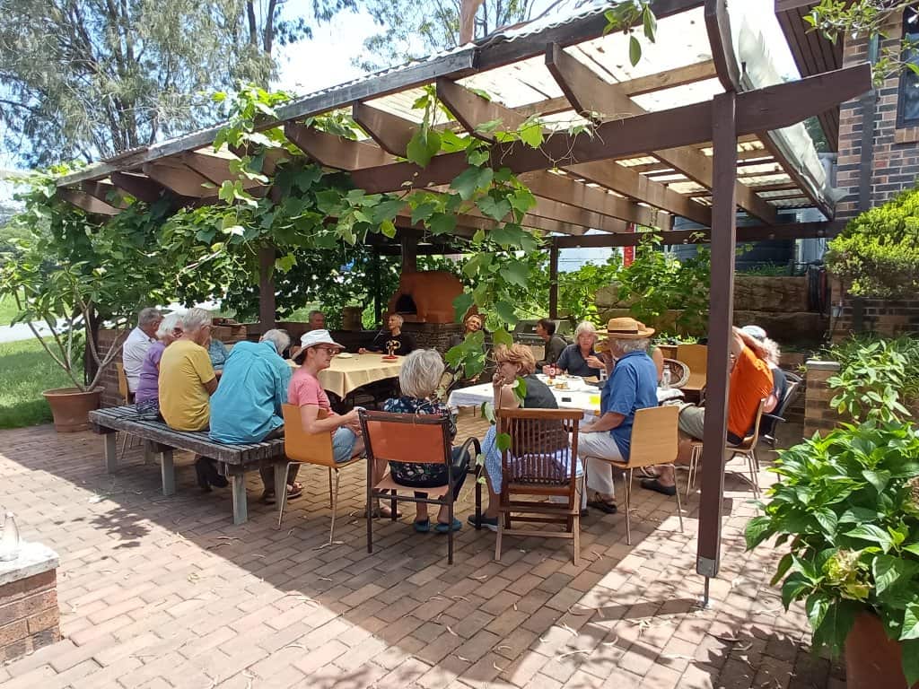 A group of people sitting on a shady patio having lunch.