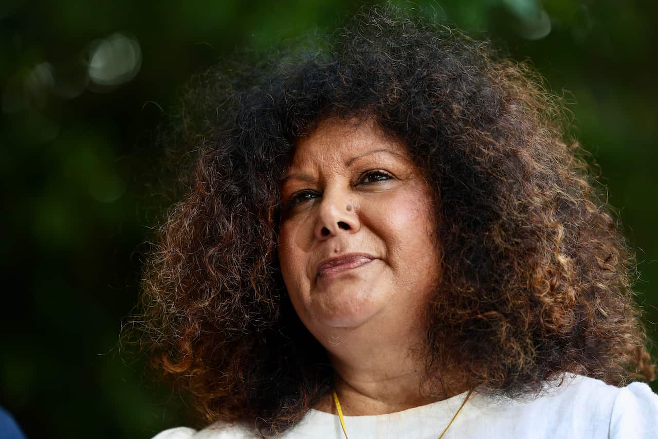 Close-up of a woman with dark frizzy hair and wearing a white top