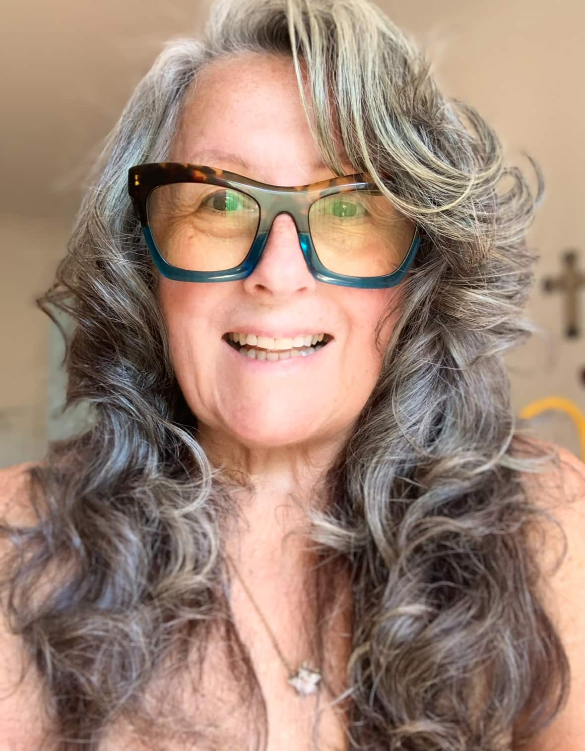 a woman with long wavy grey hair wearing glasses 