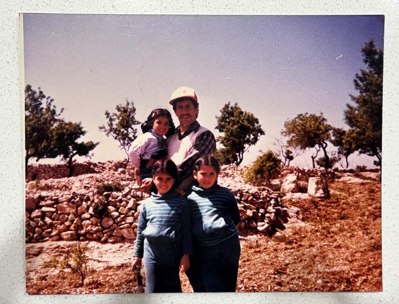 a retro film photo of a man hlding a young girl with two girls standing in front of him