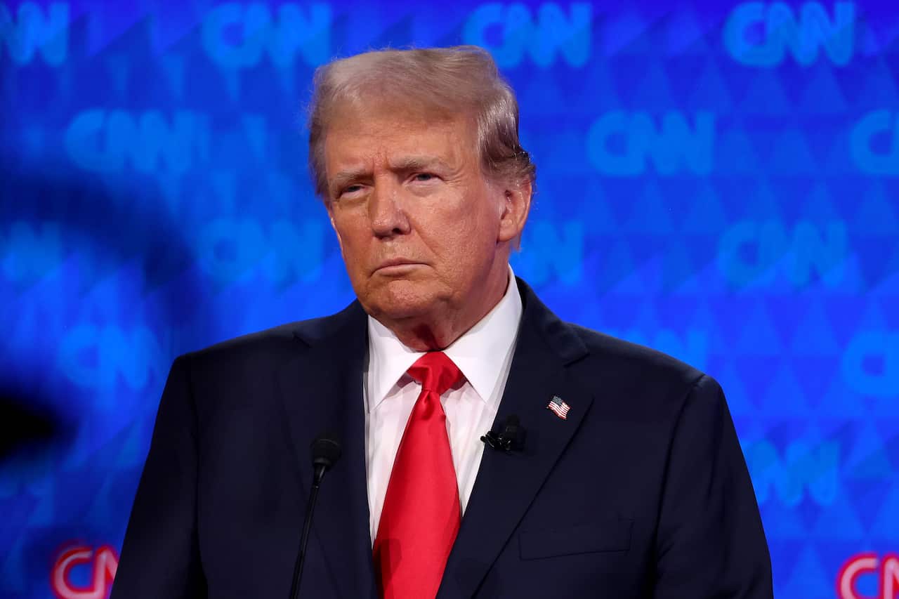 Donald Trump stading in front of a blue background with the CNN logo.