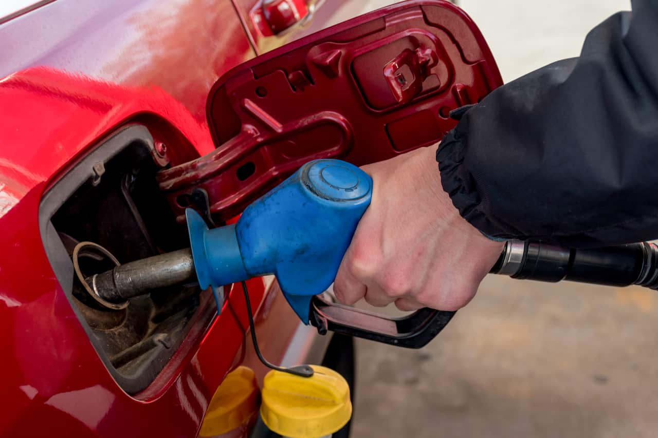 A man hand holding pump filling gasoline. 