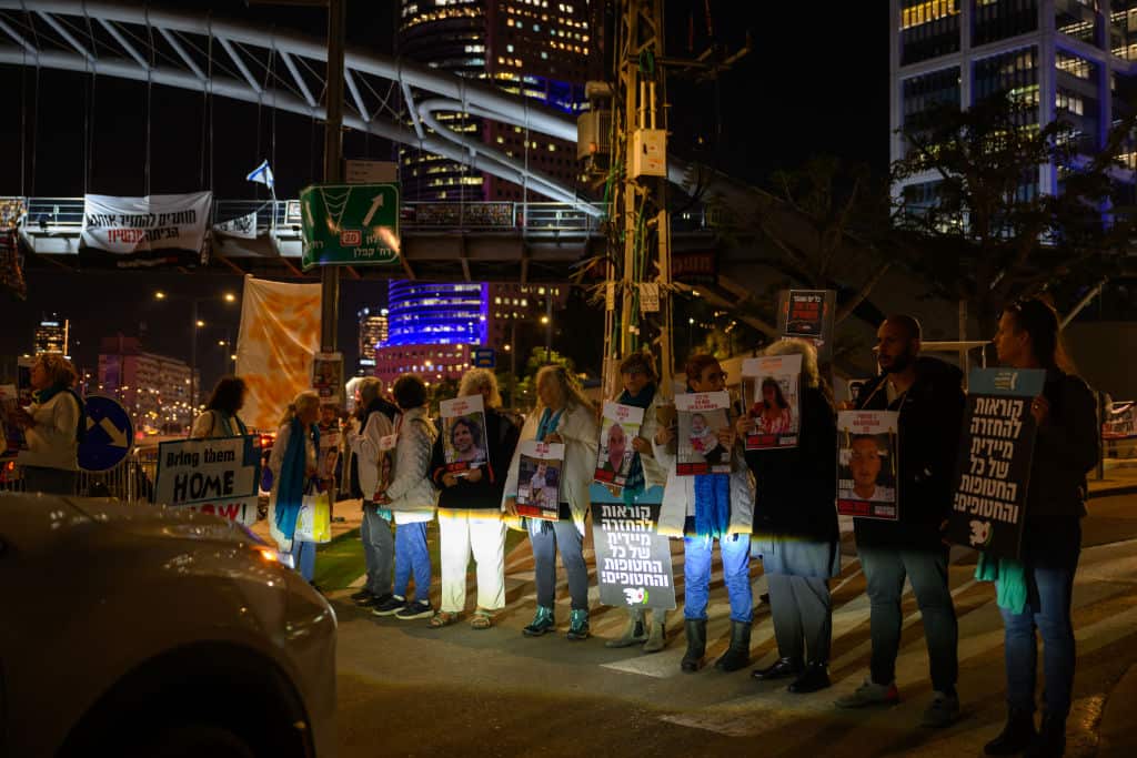 People standing outside a building a night holding placards