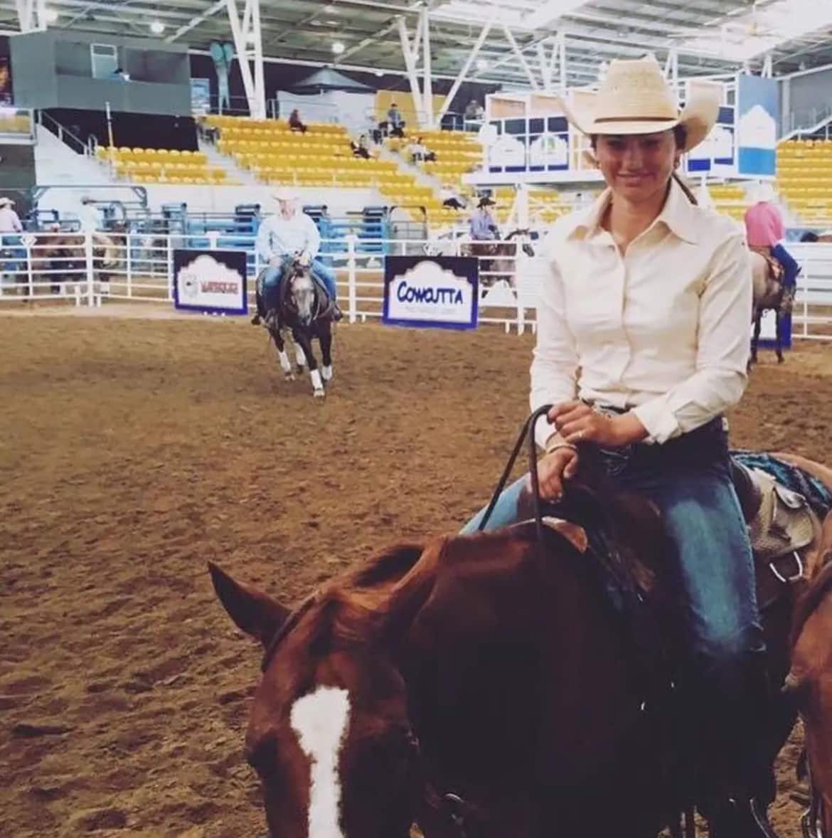 A woman smiles as she sits on a horse.