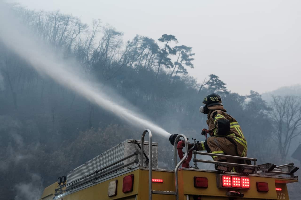 A firefighter spraying a hose from the top of a firetruck.