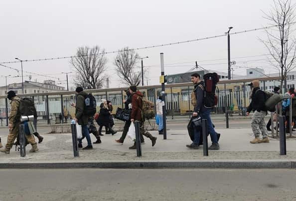 Men carrying bags walk on street next to Lviv train station, Ukraine.