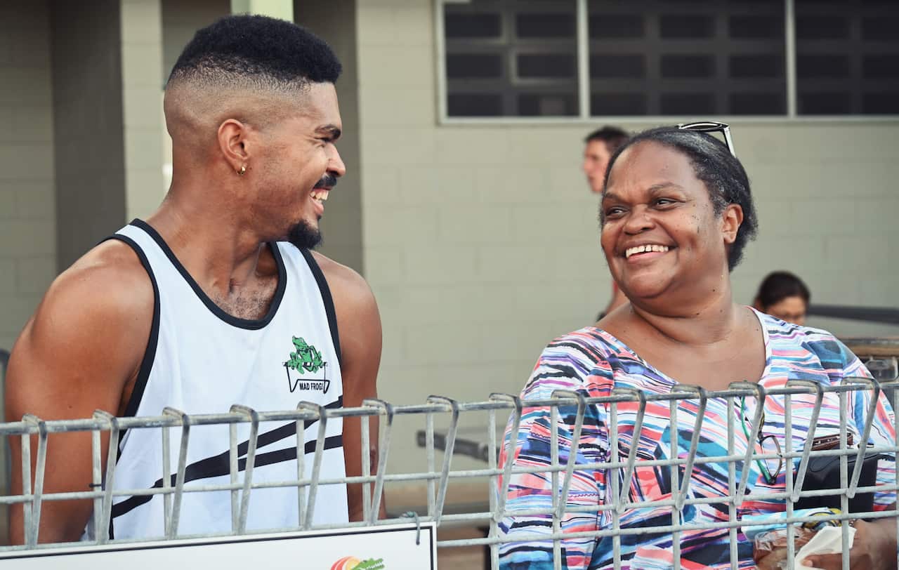 A man in a white singlet smiles at a woman wearing a colourful top