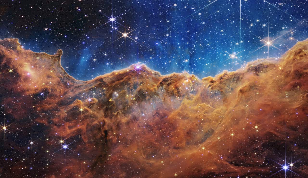 What looks much like craggy mountains on a moonlit evening is actually the edge of a nearby, young, star-forming region NGC 3324 in the Carina Nebula. 