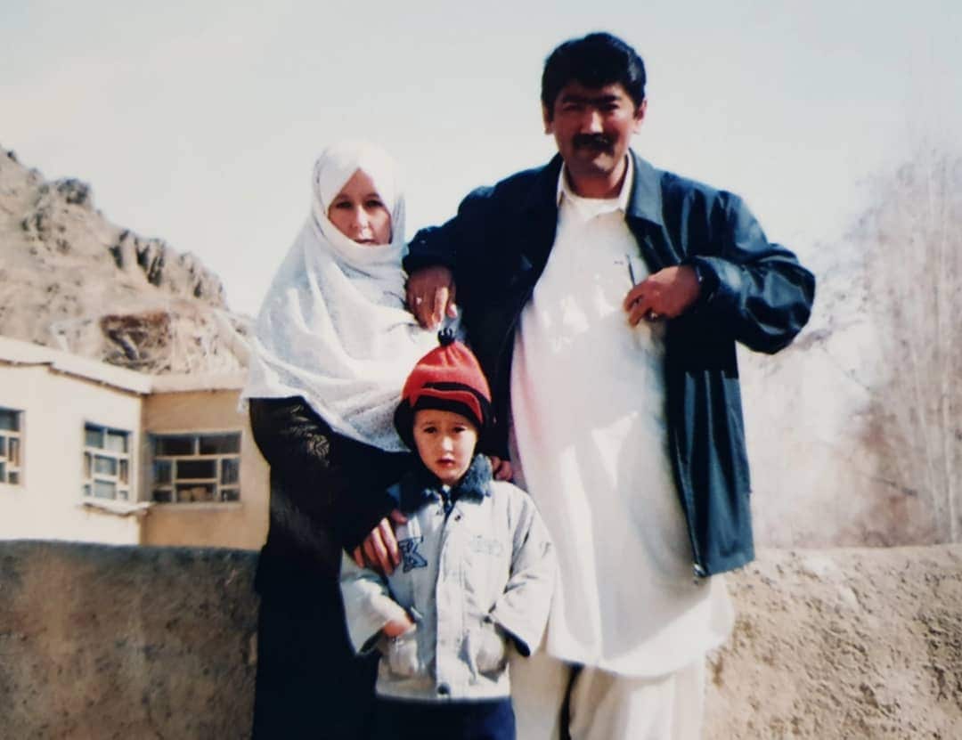 A woman man and child standing in front of a low wall