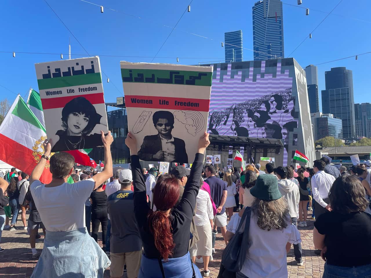 Protesters holding up Women Life Freedom protest signs.