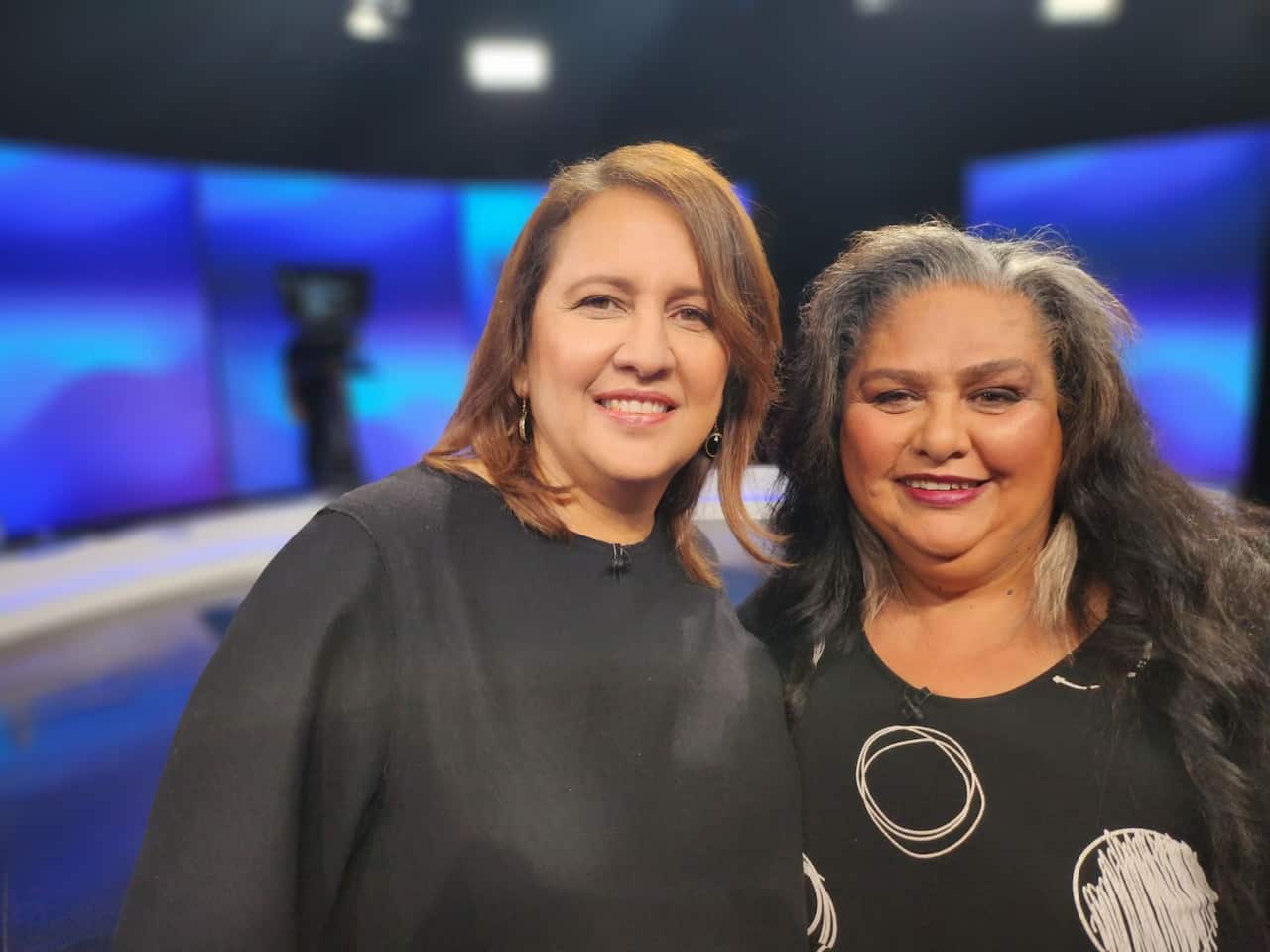 Two women pose for the camera in the SBS Insight TV studio.
