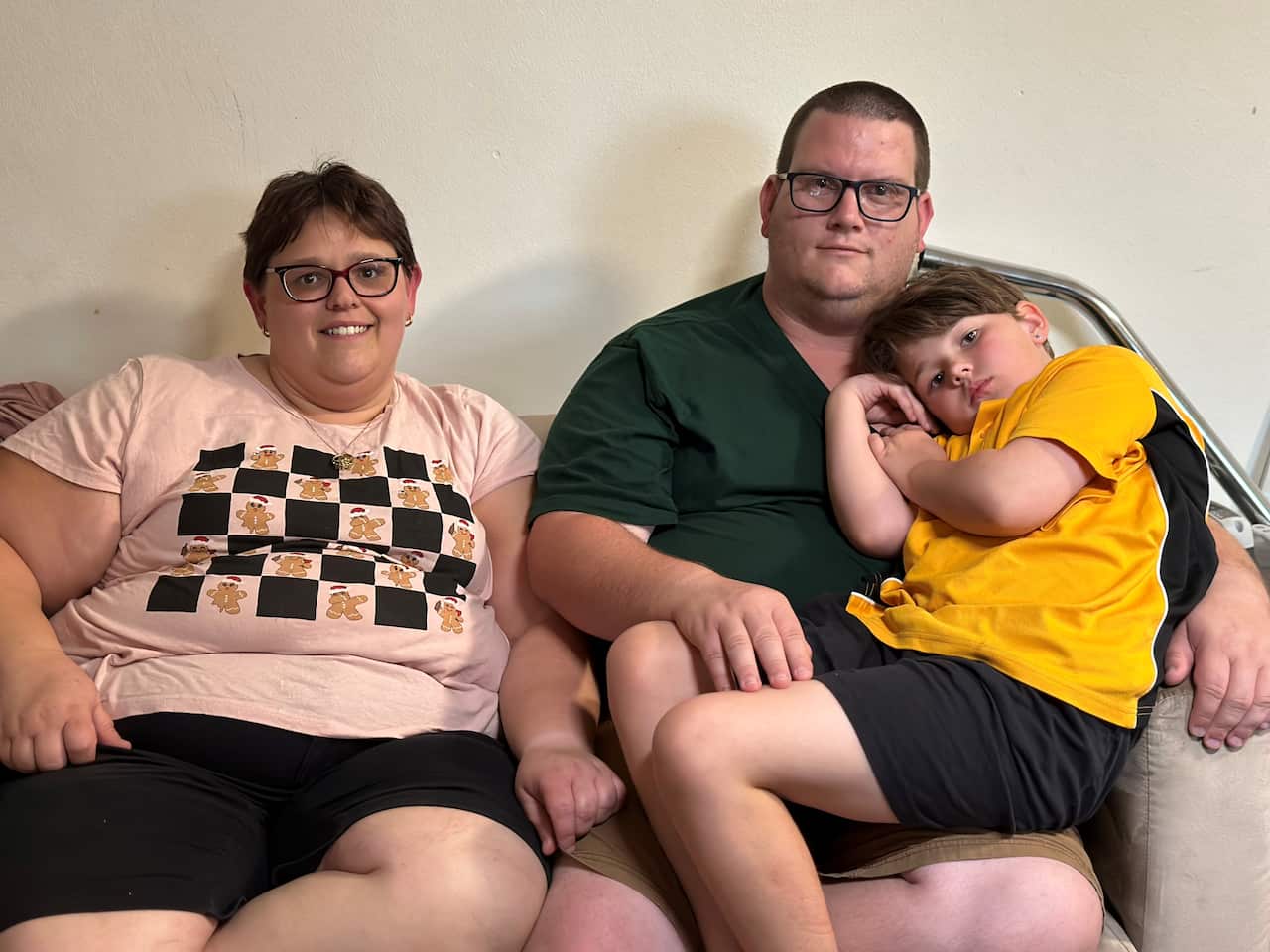 A man and a woman sit on a couch. A young child is sitting on the man's lap.
