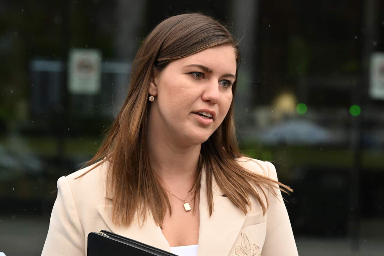 A lady in a cream suit holding a folder. 