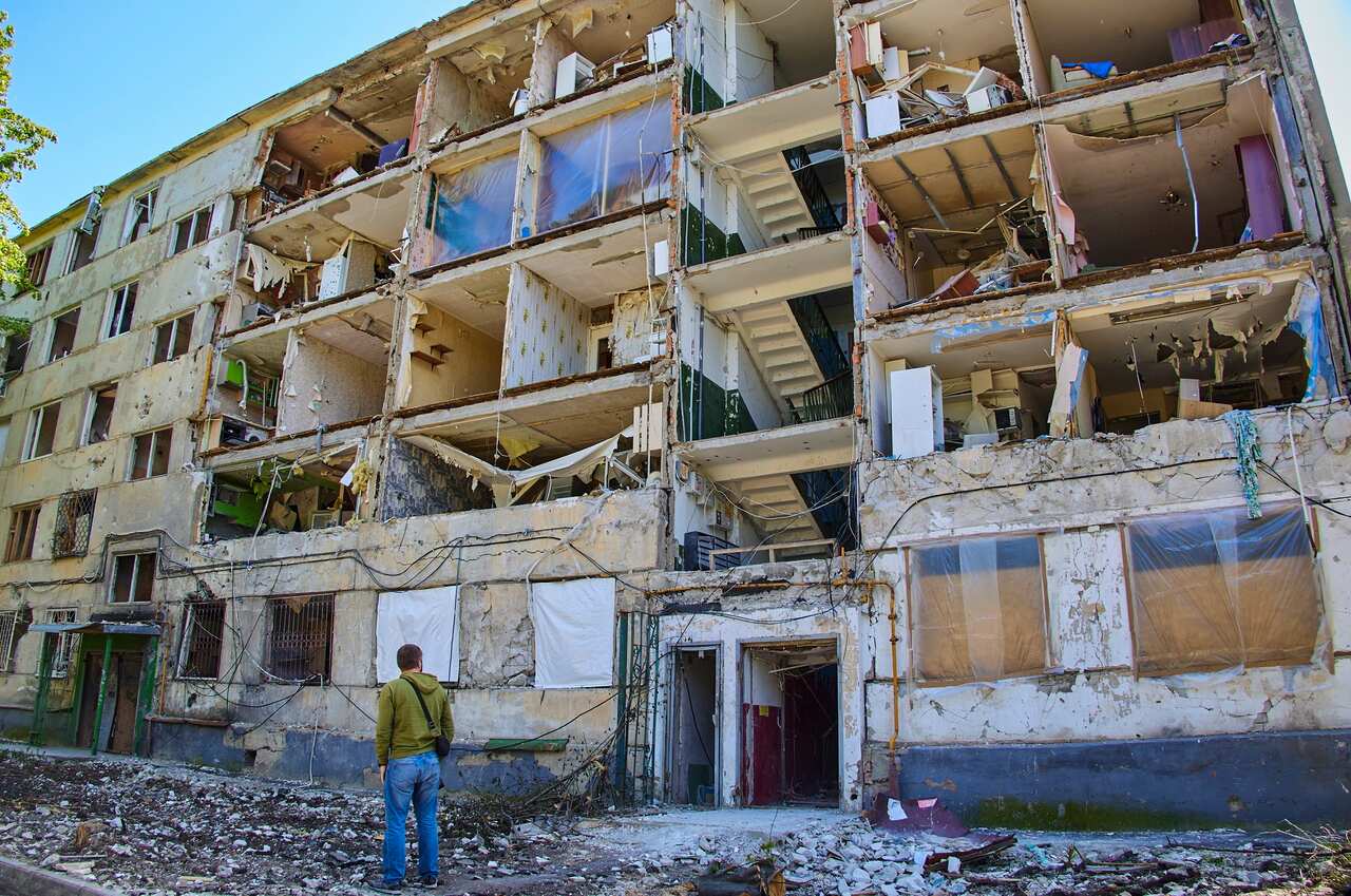 A local man looks at a residential building damaged during shelling in Kharkiv, Ukraine on 12 May 2022. 