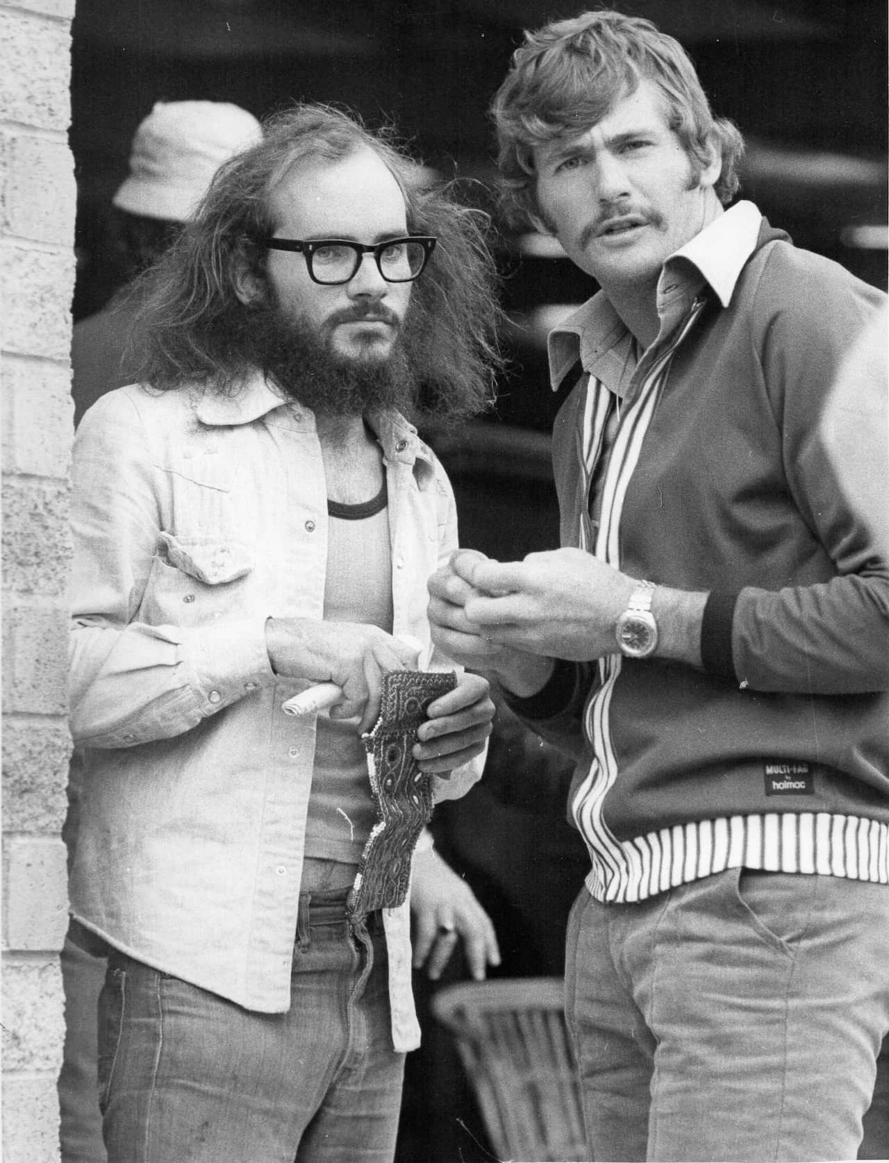 A black and white image from 1975 of two men with neutral expressions looking at the camera. 