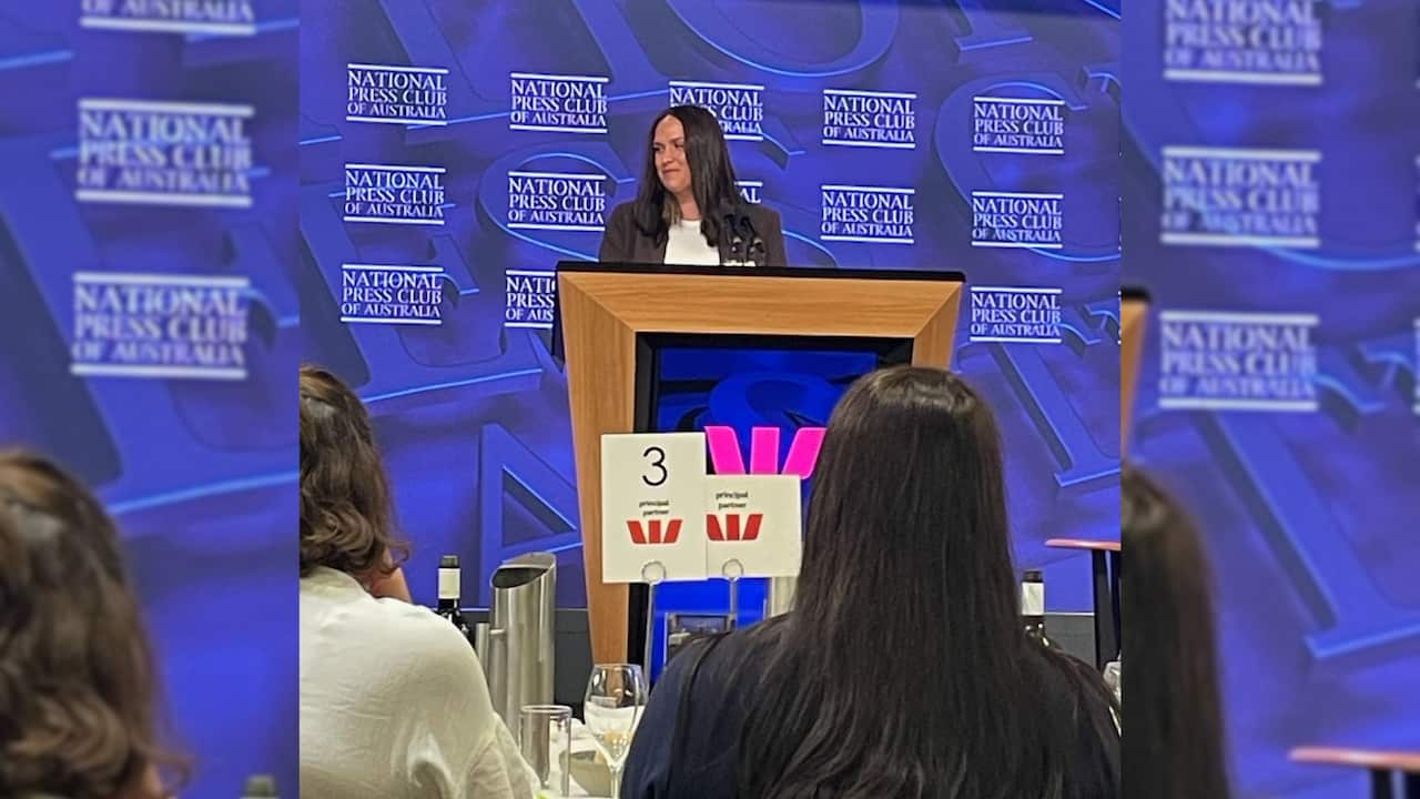 a young brunette woman at a lecturn presenting at a function