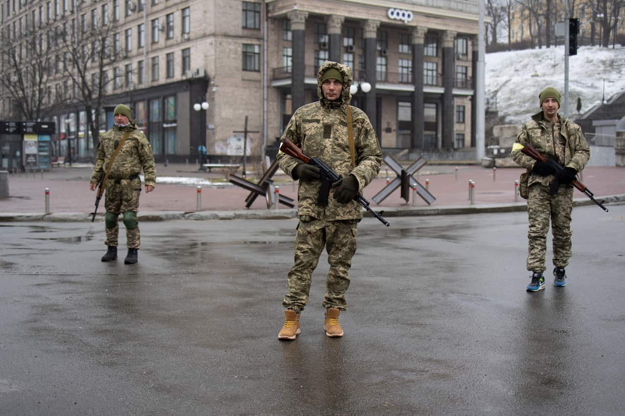 Three troops are seen standing on a street in Ukraine.