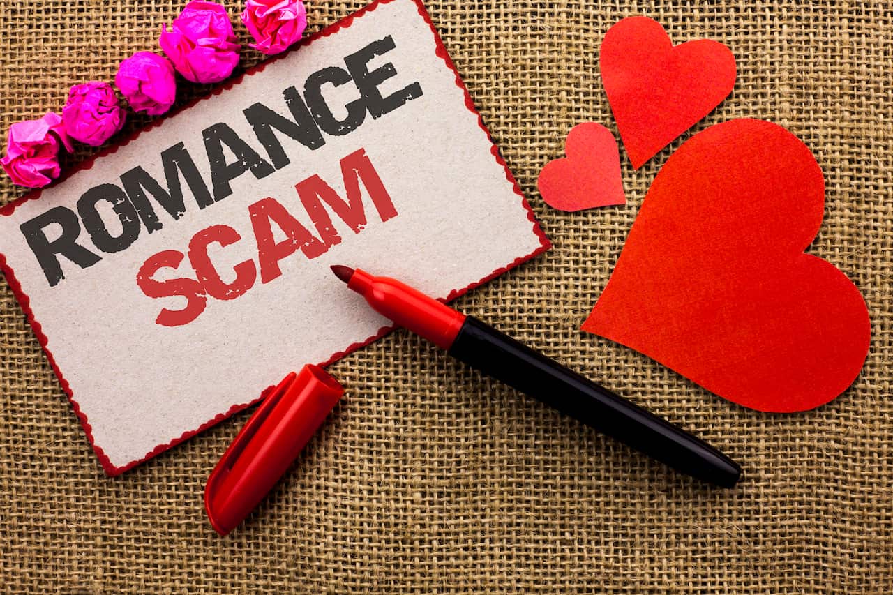 Word writing text Romance Scam. Business concept for Dating Cheat Love Embarrassed Fraud Cyber Couple Affair written on Cardboard Piece on the jute background Marker and Hearts next to it.