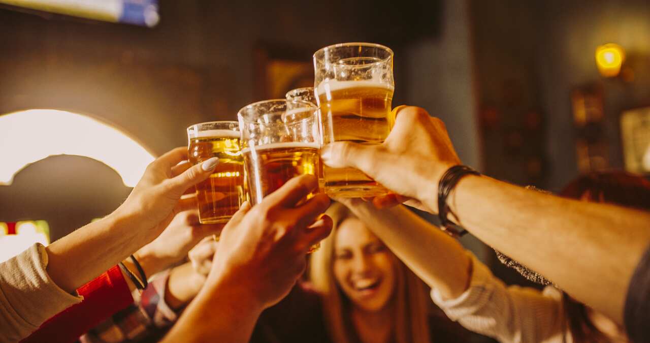 A group of people raises their glasses filled with beer in a toast.